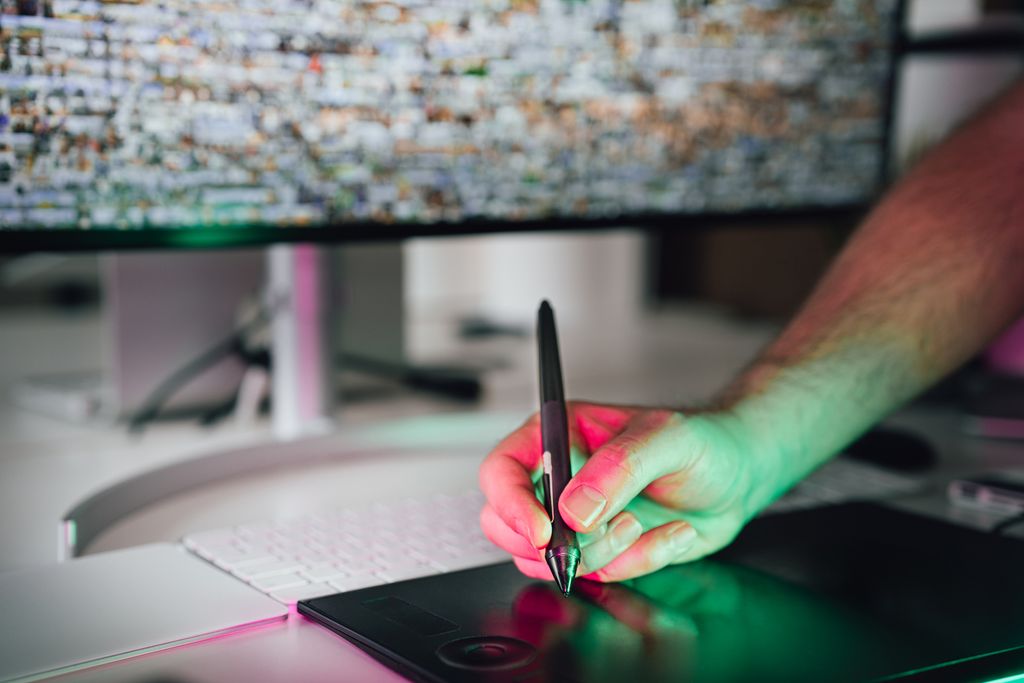 A digital artist using a graphics tablet and stylus in a modern workspace. High-tech creative process.